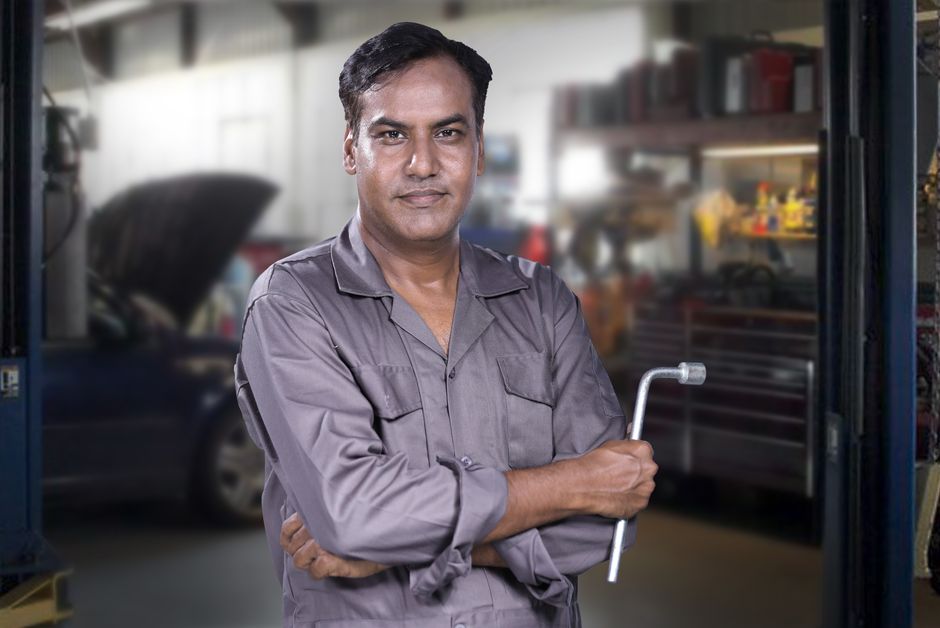 Smiling auto mechanic standing in tire shop